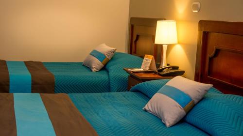 a hotel room with two beds and a telephone at Hotel y Restaurante El Guarco in Cartago