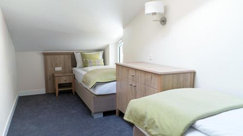 a small bedroom with two beds and a dresser at Hotel Quellenhof in Grainau