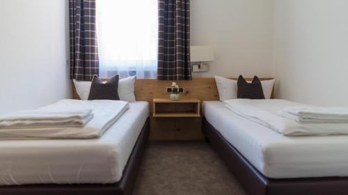 two twin beds in a room with a window at Hotel Quellenhof in Grainau