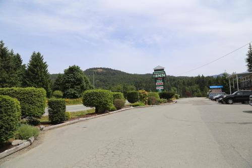 an empty street with a gas station sign and trees at Timberlodge RV & Campground in Port Alberni