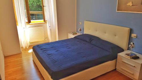 una camera da letto con un letto con lenzuola blu e una finestra di Appartamento Angi - lago & vacanza attiva a Riva del Garda
