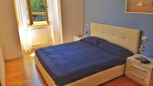 sypialnia z łóżkiem z niebieskimi prześcieradłami i oknem w obiekcie Appartamento Angi - lago & vacanza attiva w mieście Riva del Garda