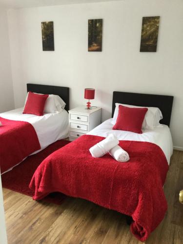 um quarto com 2 camas com lençóis vermelhos e brancos em 4 Bed House next to Basildon Town Centre em Basildon