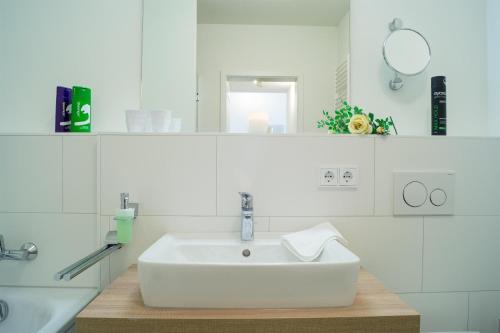ein weißes Badezimmer mit einem Waschbecken und einem Spiegel in der Unterkunft Südkap A-03 in Pelzerhaken