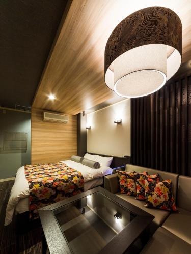 a bedroom with a bed and a couch and a chandelier at Hotel Tosu Tsukasa (Love Hotel) in Tosu