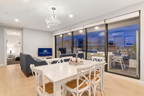 a white dining room with a white table and chairs at The Hamptons Apartments - Port Melbourne in Melbourne