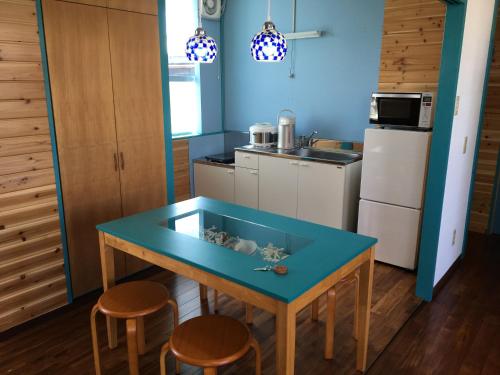 une cuisine avec une table bleue et deux tabourets dans l'établissement Dolphins and Whales, à Ishigaki