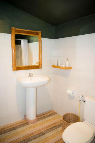 a bathroom with a sink and a mirror and a toilet at Oasis Yoga Bungalows in Ko Lanta