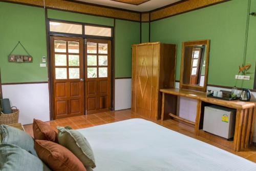 a bedroom with green walls and a bed and a mirror at Oasis Yoga Bungalows in Ko Lanta