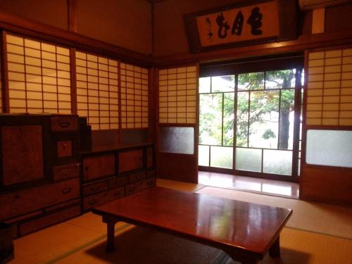 a room with a wooden table in a room with windows at Ichie in Tanabe