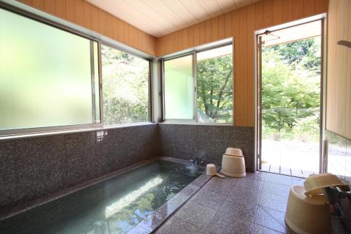 a bathroom with a large tub with windows at Yadori Onsen Iyashinoyu in Hashimoto