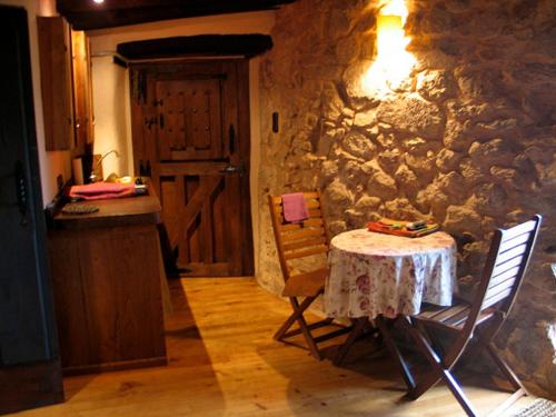 una cucina con tavolo, sedie e parete in pietra di Apartamento La Muralla a Miranda del Castañar