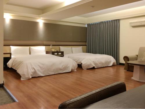 a hotel room with two beds and a couch at Zaw Jung Business Hotel in Taichung