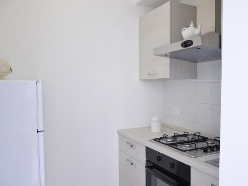 a white kitchen with a stove and a refrigerator at Duca70 "Suite Home" in Taranto