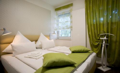 Cama blanca con almohadas verdes y blancas y ventana en Am Schmeding en Berlín