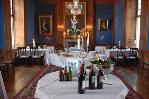 a dining room with white tables and bottles of wine at Kronovalls Vinslott in Skåne-Tranås