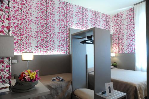 a bedroom with pink floral curtains and a mirror at Hotel Astoria in Ravenna