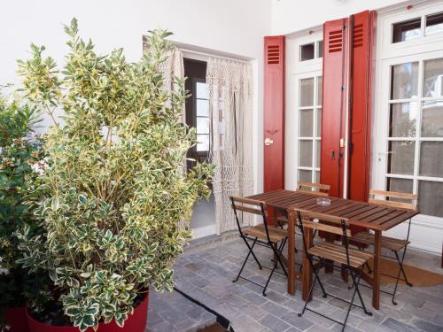 アルカションにあるCAP BERILOU . Qualité et Confort Assuré .の木製のテーブルと椅子、植物のあるパティオ
