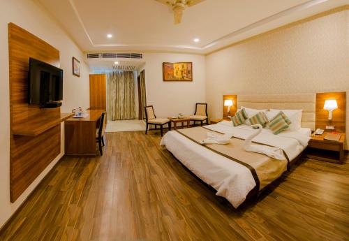 バラナシにあるThe India Benaresの大型ベッドとテレビが備わるホテルルームです。