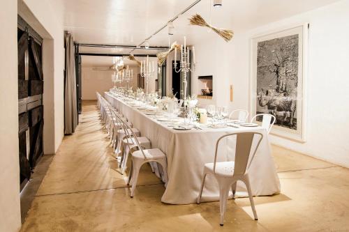 a long table with white chairs and a long table at Cradle Boutique Hotel in Lanseria