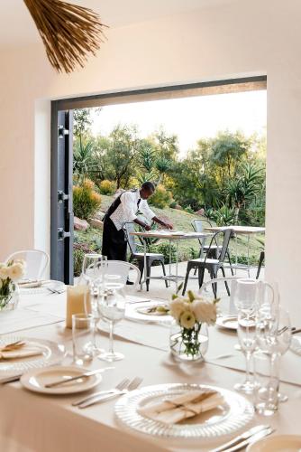 a man sitting at a table in front of a window at Cradle Boutique Hotel in Lanseria