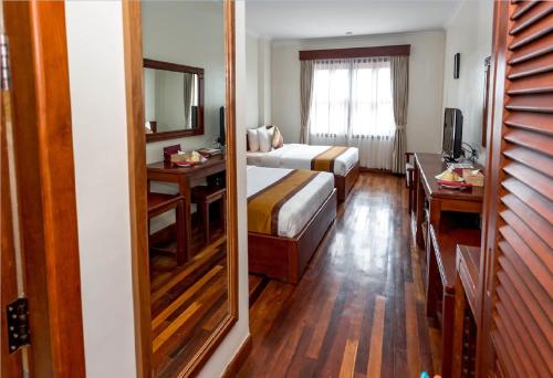 a bedroom with a bed and a desk and a mirror at Saem Siemreap Hotel in Siem Reap