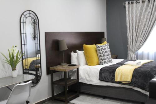 a bedroom with a bed with a mirror and a desk at 93 on Celliers Guesthouse in Louis Trichardt