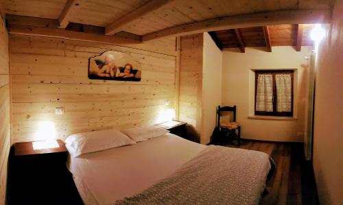 a bedroom with a white bed in a wooden wall at Il Borgo Dei Celti in Fiumalbo