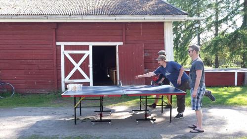 two men standing around a ping pong table in front of a barn at Koljonvirran Kartano in Iisalmi