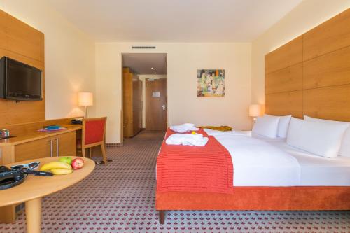 ヴァーネミュンデにあるパークホテル ヒューブナーの大きなベッドとテーブルが備わるホテルルームです。