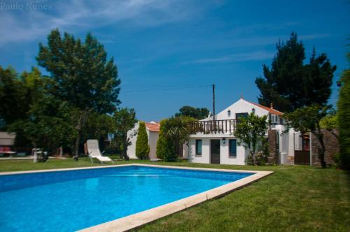 a villa with a swimming pool in front of a house at Casa Da Noquinhas in Bunheiro
