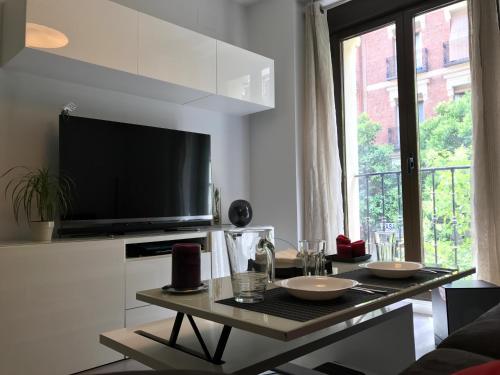 ein Wohnzimmer mit einem Tisch und einem Flachbild-TV in der Unterkunft Moderno apart centro in Madrid