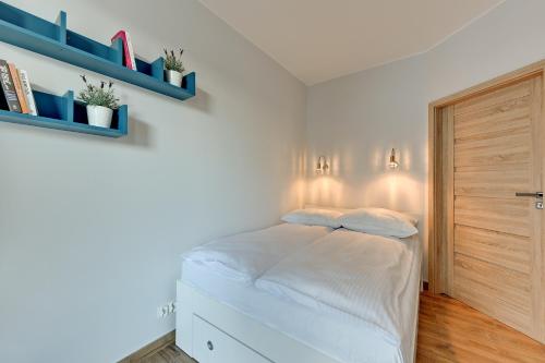 a small bedroom with a bed and blue shelves at INA Rent - Tre Mare Apartamenty in Gdańsk