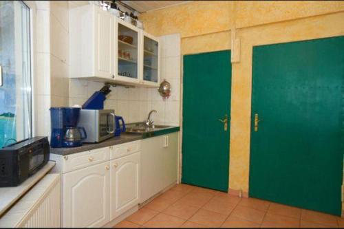 eine Küche mit grüner Tür und weißen Schränken in der Unterkunft Ferienwohnung für 4 Personen in Sassnitz in Sassnitz