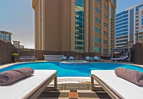 a hotel swimming pool with two beds and buildings at Somewhere Hotel Apartment in Dubai