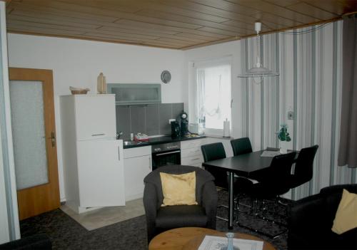 a living room with a kitchen and a table with chairs at Haus am Stryckweg in Willingen
