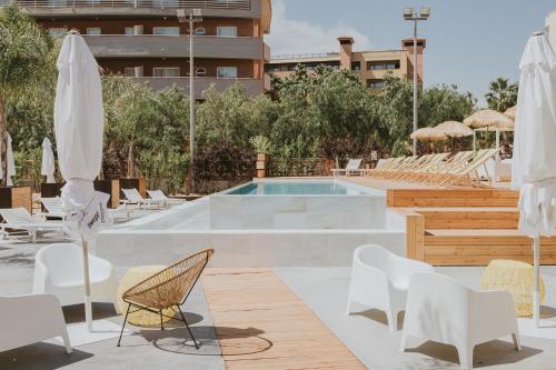 
a pool with chairs, tables, chairs and umbrellas at Palas Pineda in La Pineda
