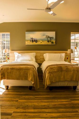 a bedroom with two beds and a painting of a rhino at Polo Guest House in Polokwane