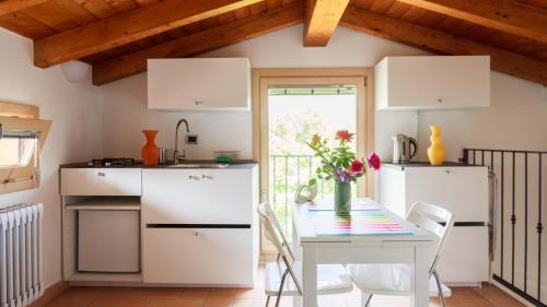 una cocina con armarios blancos y una mesa con flores en B&B Nido Sui Laghi, en San Donnino della Nizzola