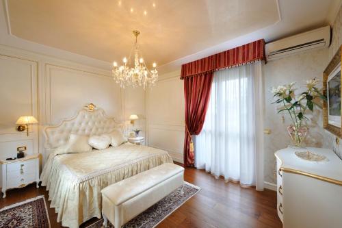 a bedroom with a bed and a chandelier at Hotel Ca' D'Oro in Bibione