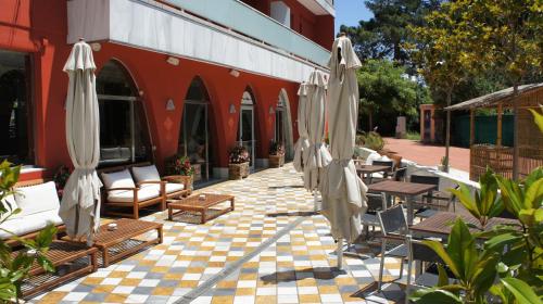 an outdoor patio with umbrellas and chairs and tables at Hotel Spa Pinar del Mar in Platja  d'Aro