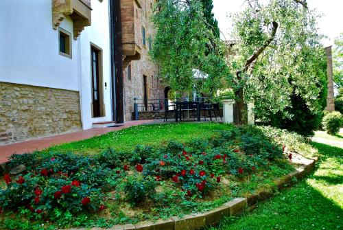 a garden with red flowers in the grass next to a building at Borgo La Casaccia in Montaione