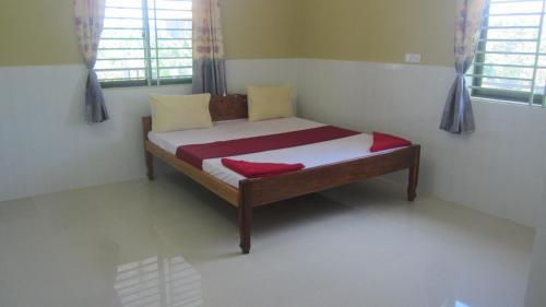 a small bed in a room with two windows at Phalla Riverside in Kampong Cham