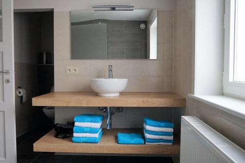 y baño con lavabo y toallas azules. en villa mezennestje en Oostduinkerke