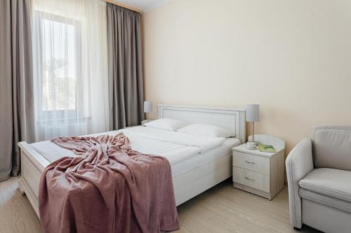 a white bedroom with a bed and a chair at Asiya in Odesa