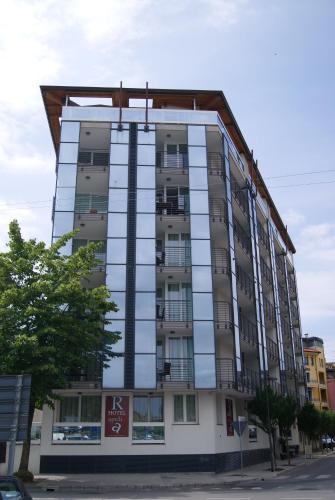 a tall building with glass windows on a street at Residence Aprilia in Grado