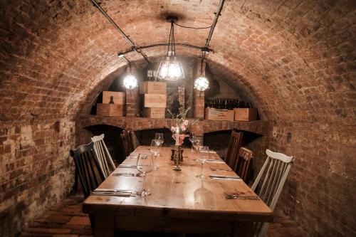 a long wooden table in a brick room with chairs and glasses at Hinds Head in Aldermaston