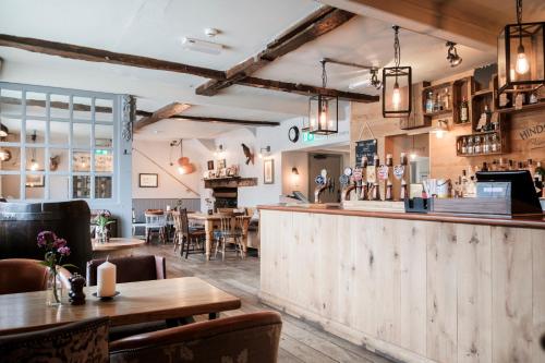 a restaurant with a bar with tables and chairs at Hinds Head in Aldermaston