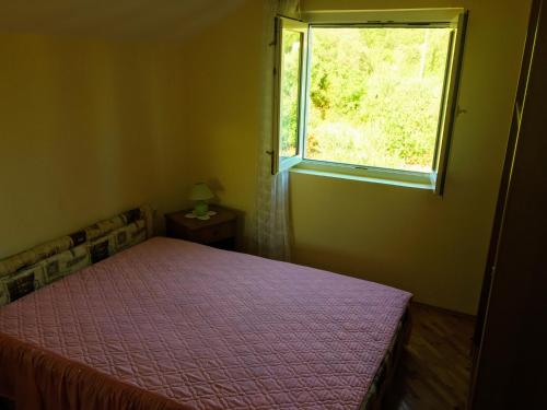 a bedroom with a bed and a window at Apartment Grubelic in Prvić Šepurine