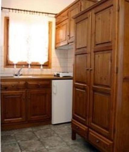 a kitchen with wooden cabinets and a white refrigerator at Spitalia Studios in Skopelos Town